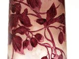 a glass vase with red leaves on it on a white surface