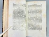 an open book with a pen resting on top of it on a table