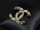 a close up of a black pillow with a silver chanel brooch