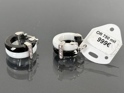 pair of black and white hoop earrings with diamonds on a black surface