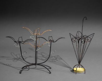 deux sculptures métalliques représentant des fleurs et un bougeoir posés sur une surface grise