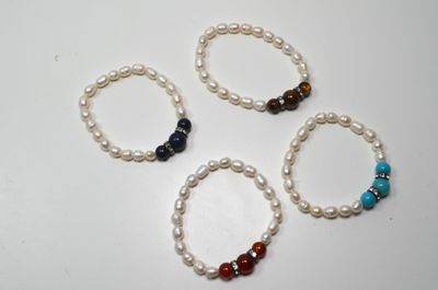 quatre bracelets ornés de perles et de pierres précieuses sont disposés sur un fond blanc
