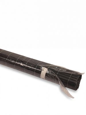 un fagot de brindilles enveloppé dans du papier noir posé sur une surface blanche