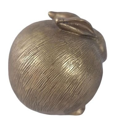 a gold apple with a leaf on top of it