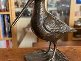 une statue représentant un oiseau perché sur une table en bois
