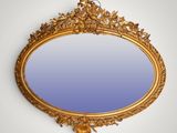 an oval mirror with a gold frame and a blue background