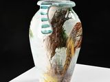 a vase with a painting on it sitting on a table