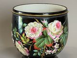 a black vase with pink and white flowers painted on it