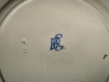 a close up of a white plate with a blue monogram on it