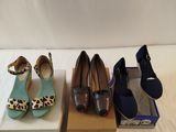 three pairs of women ' s shoes sitting on top of boxes on a bed
