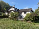 the house is in the middle of a grassy field with trees