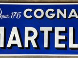 un panneau bleu sur lequel est inscrit « Cognac Martell »