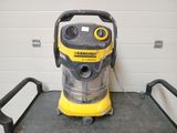 un aspirateur jaune et noir posé sur un chariot dans une pièce