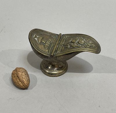 a small metal object with a walnut in it