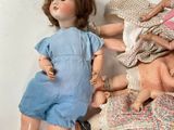 a doll laying on the ground next to a pile of dolls