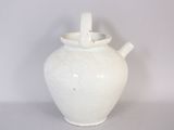 a white vase with a handle sitting on a table
