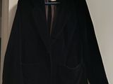 black blazer jacket hanging on a hanger in a white room