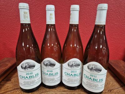four bottles of wine are lined up on a wooden table