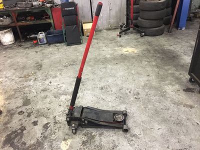 une photo d'un cric de sol rouge et noir dans un garage