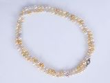 a close up of a white and yellow pearl necklace on a white surface