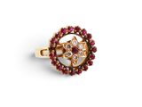 gros plan d'une bague en or avec des pierres rouges et blanches