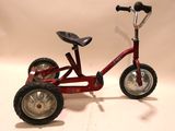 a red tricycle with a black seat and a black seat