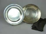 two silver plates sitting next to each other on a table