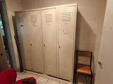 a red chair in the corner of a room next to lockers