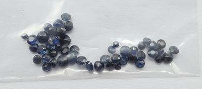 un sachet de saphirs bleus posé sur une surface blanche