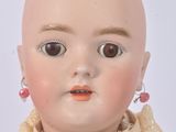 a small doll with a bald head and pink earrings