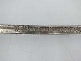 an old silver knife with writing on it sitting on a white surface