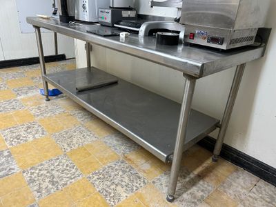 une table en acier inoxydable sur laquelle est posée une cafetière