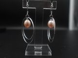 boucles d'oreilles en forme d'anneaux, en perles et argent, présentées sur un support en acrylique transparent