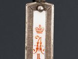 a close up of a silver and enamel pendant with a crown on it