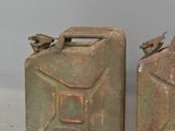 pair of old metal jerry cans sitting on top of a cement floor
