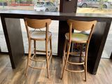 two wooden stools in front of a table with a clock on it