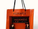an orange shopping bag with two mannequins in it