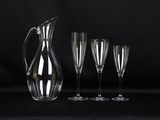 a set of four wine glasses and a pitcher on a black background