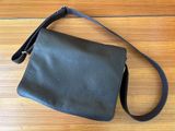 a black purse sitting on top of a wooden floor next to a wooden floor