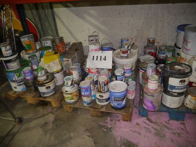 many cans of paint on a pallet in a garage