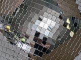 mirrored disco ball hanging from ceiling with reflection of a person in the mirror