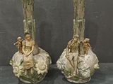 two vases that have statues on them on a table