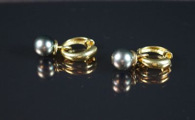 paire de boucles d'oreilles en or et perles sur fond noir avec reflets