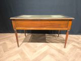 an old wooden desk with a glass top on a wooden floor