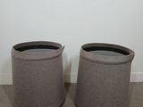 a pair of round stools in grey fabric with a black top