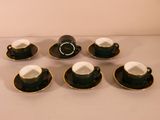 six black and white coffee cups and saucers sitting on a table