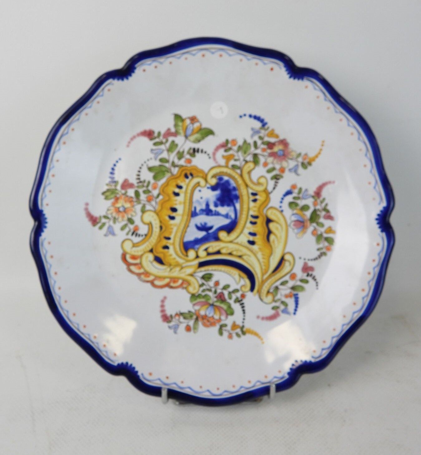 E. GEORGES à Nevers. Assiette décorative en faïence à bord chantourné et à décor floral. Diam. 25,5 cm.