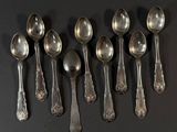 six cuillères en argent sont alignées sur une surface noire