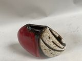 a red and black vase sitting on a white surface