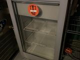 un réfrigérateur avec une porte en verre sur laquelle est collé un autocollant